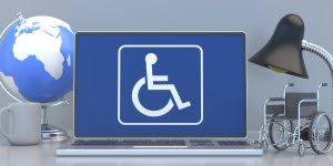 Disabled, handicapped home office concept. Wheelchair sign symbol on a laptop screen, office desk background. 3d illustration